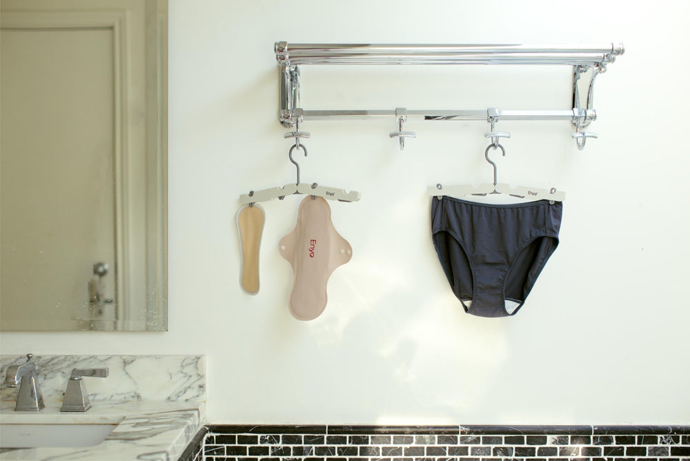 reusable menstrual pad, panty liner, and women's panty on hangers in a bright washroom