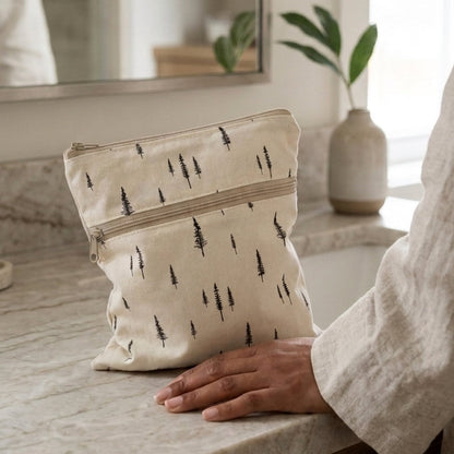 Beige pouch with tree pattern held by a person in a bathroom setting