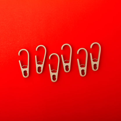 Six beige clothing clip hooks on a red background