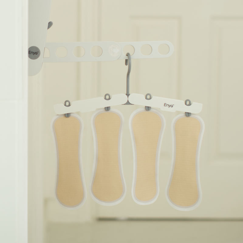 How do you care for The Stay Liner? Four reusable panty liners hang on a white drying rack, showcasing their lightweight and breathable design for easy washing and fast drying.