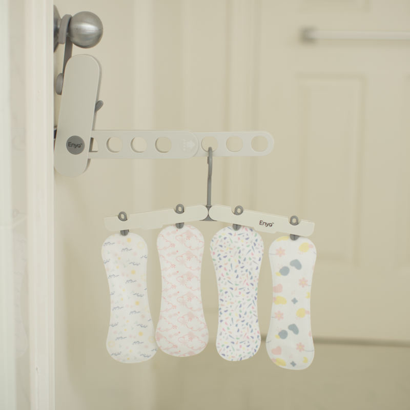 Four patterned reusable liners hanging on a hook in a washroom