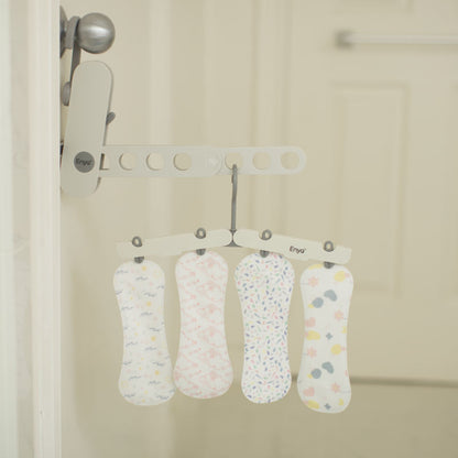 Four patterned reusable liners hanging on a hook in a washroom