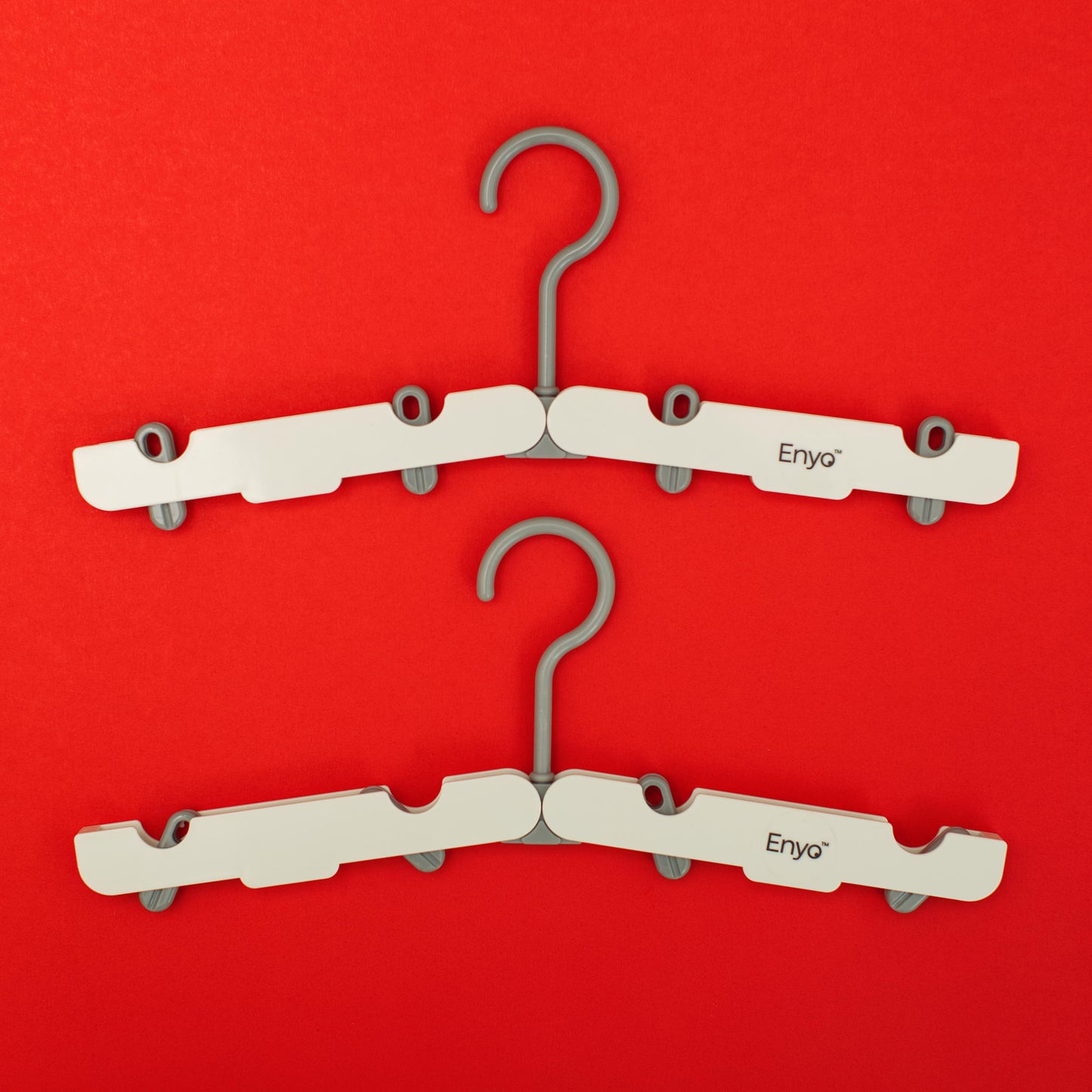 Two white and light grey plastic foldable hangers with 4 clips on a red background