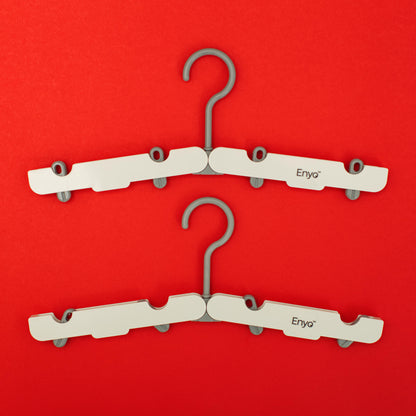 Two white and light grey plastic foldable hangers with 4 clips on a red background