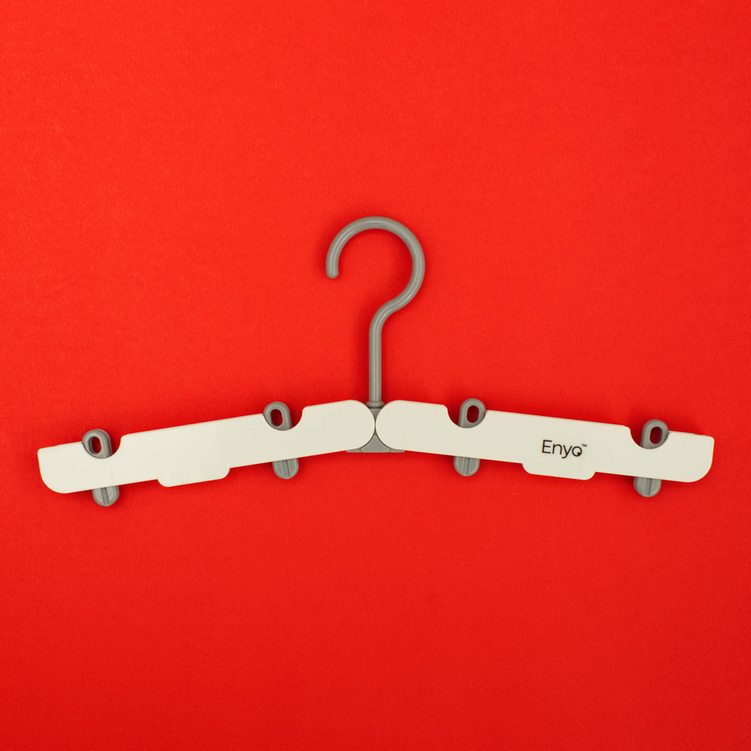 One white and light grey plastic foldable hanger with 4 clips on a red background