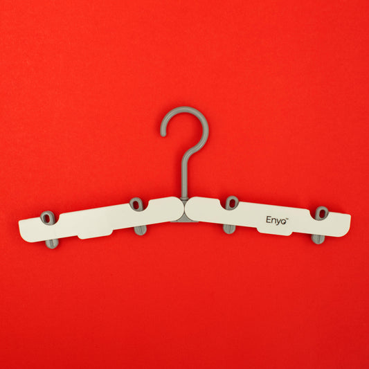 One white and light grey plastic foldable hanger with 4 clips on a red background