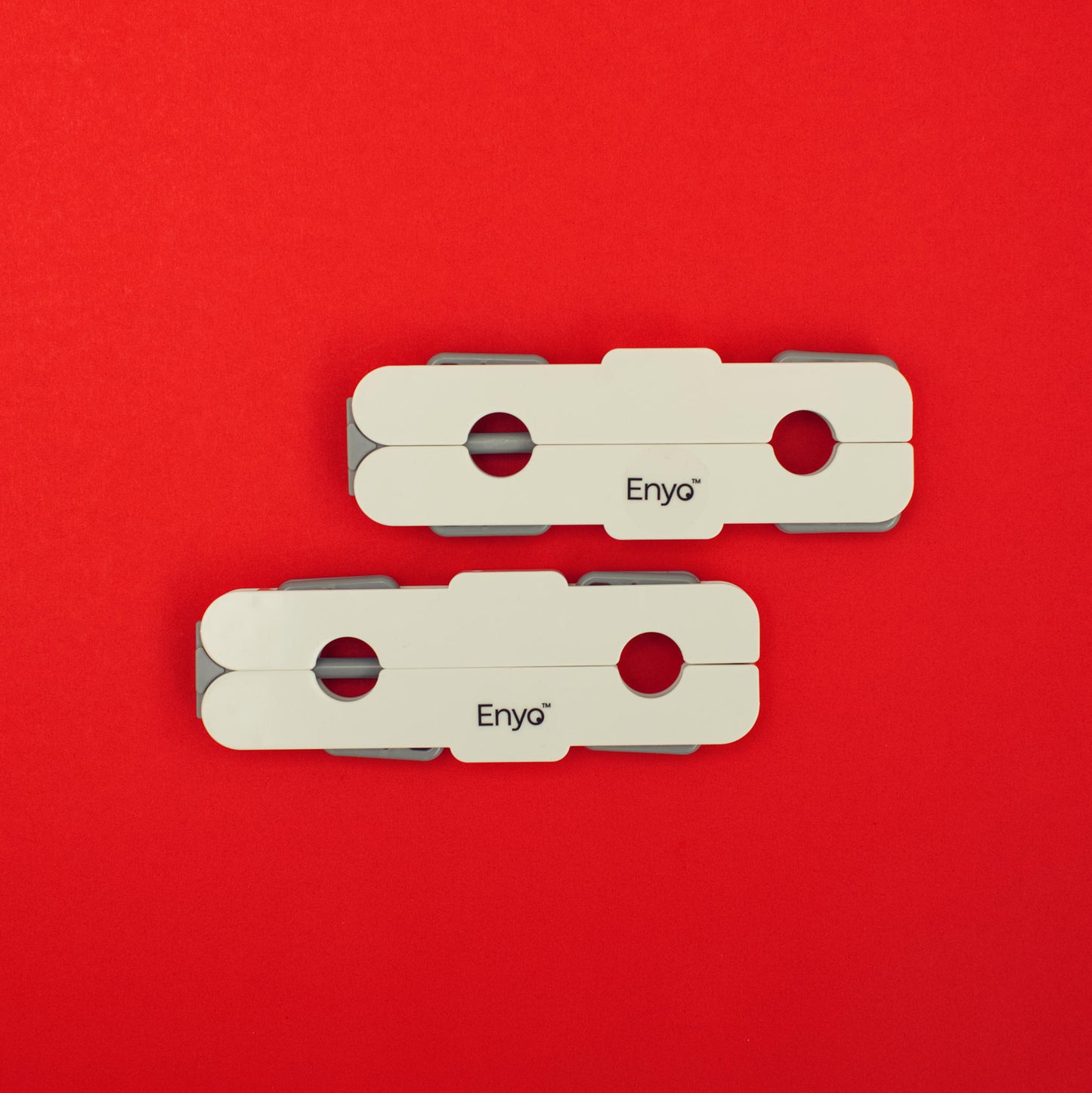 Two portable travel white and light grey plastic foldable hangers with 4 clips on a red background