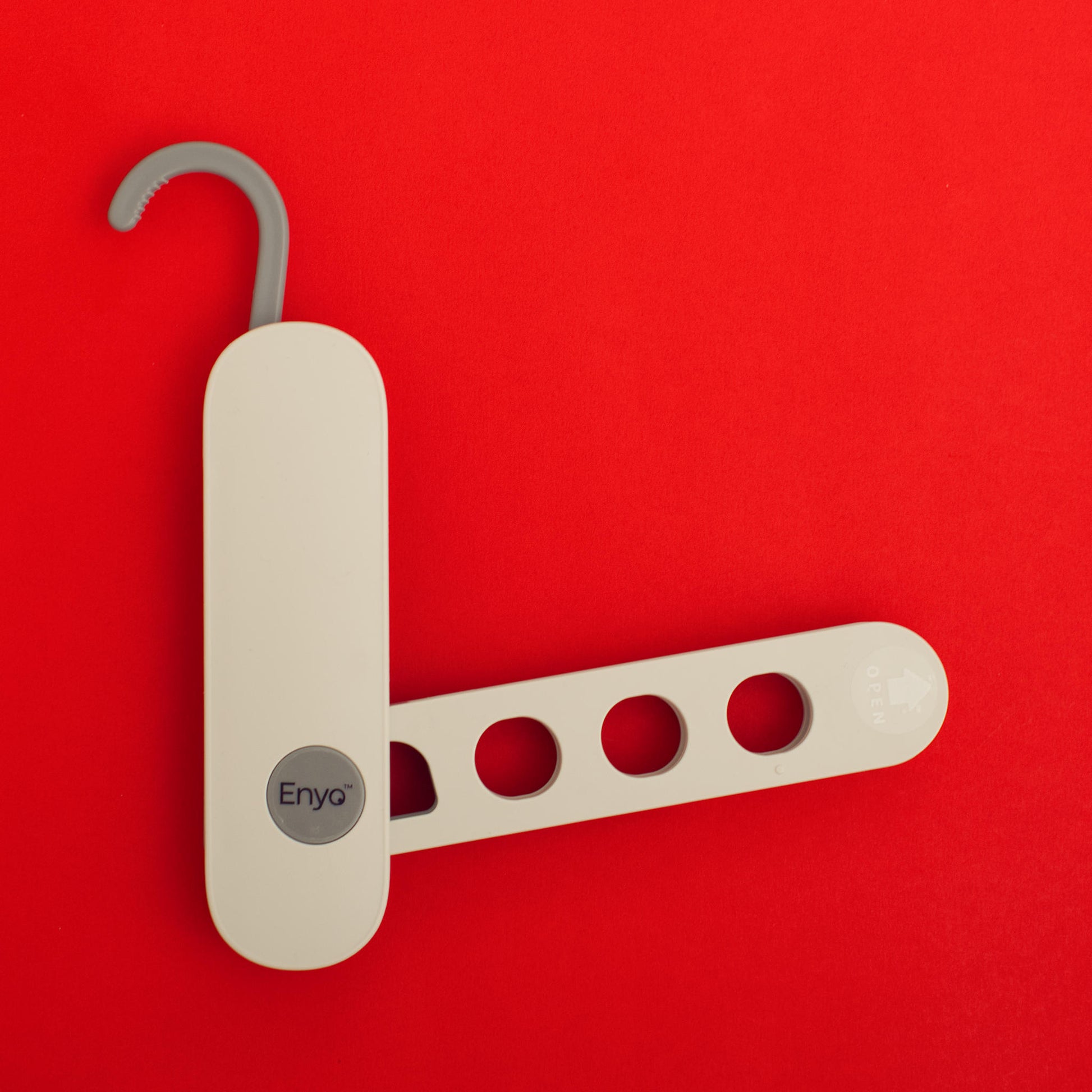 White and light grey plastic foldable hanger rack with 4 holes and a grey on a red background