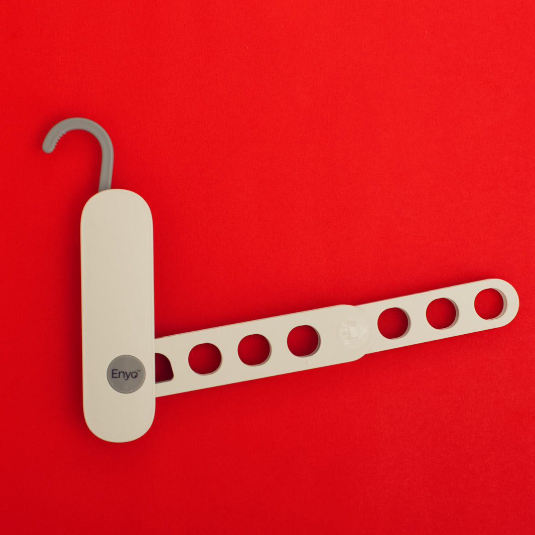 White and light grey plastic foldable hanger rack with 7 holes and a grey on a red background