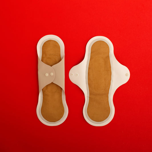 Pair of beige reusable menstrual pads with copper ion odour control top layer and SILVADUR absorbent layer with wings, on a red background