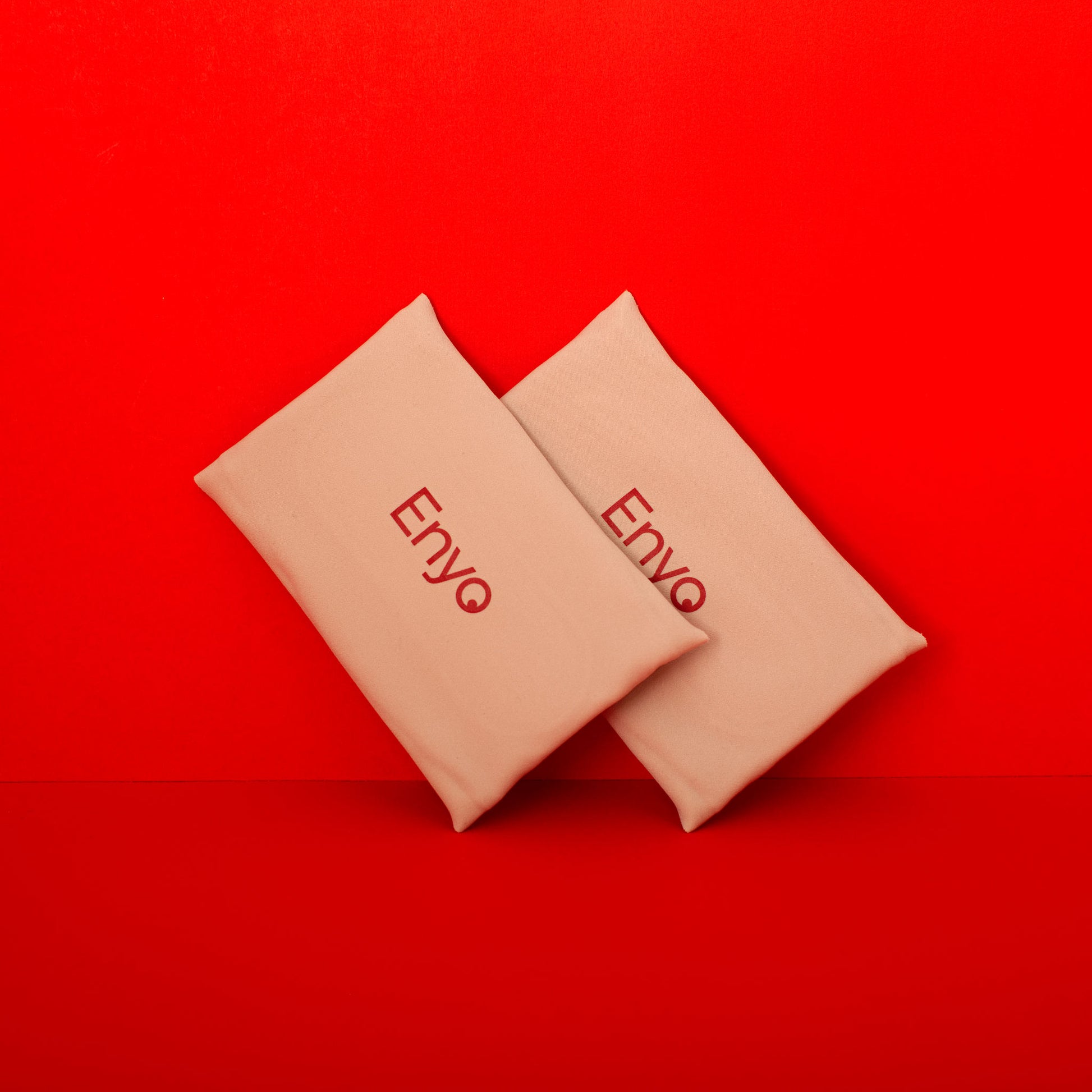 Two beige compact reusable menstrual pads, folded, with 'ENVO' branding on a red background