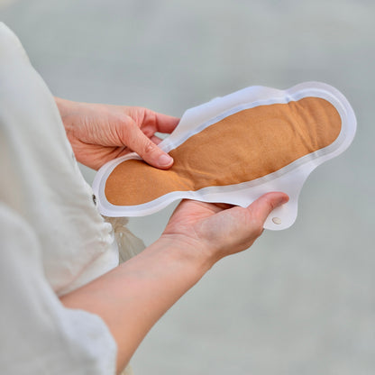 What is shown here? A close-up of hands holding an ultra-thin, lightweight reusable pad from the Complete Kit, designed for comfort, leakproof protection, and antimicrobial performance.