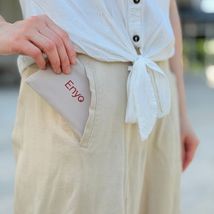 Person wearing a white shirt with a tied front and beige pants with 'Enyo' branding.