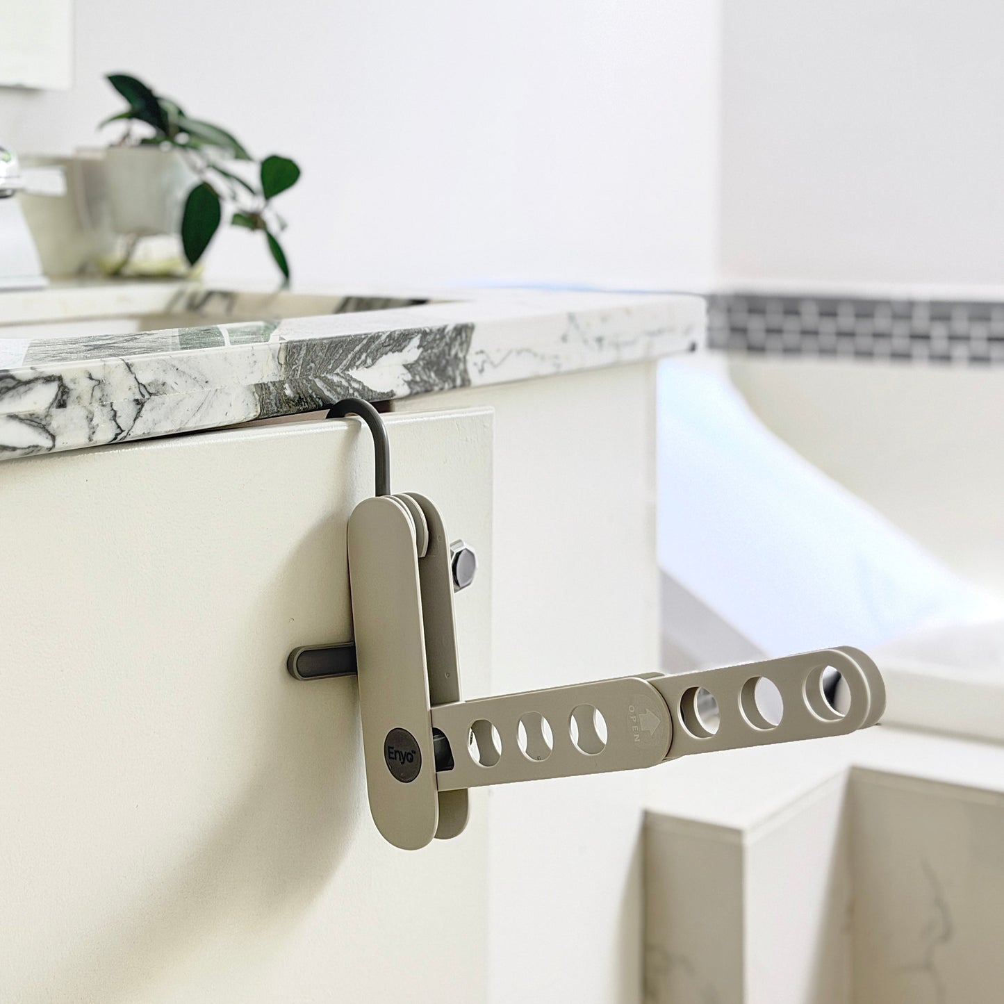 grey compact foldable hanger rack on a cabinet door in a washroom