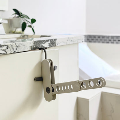 grey compact foldable hanger rack on a cabinet door in a washroom